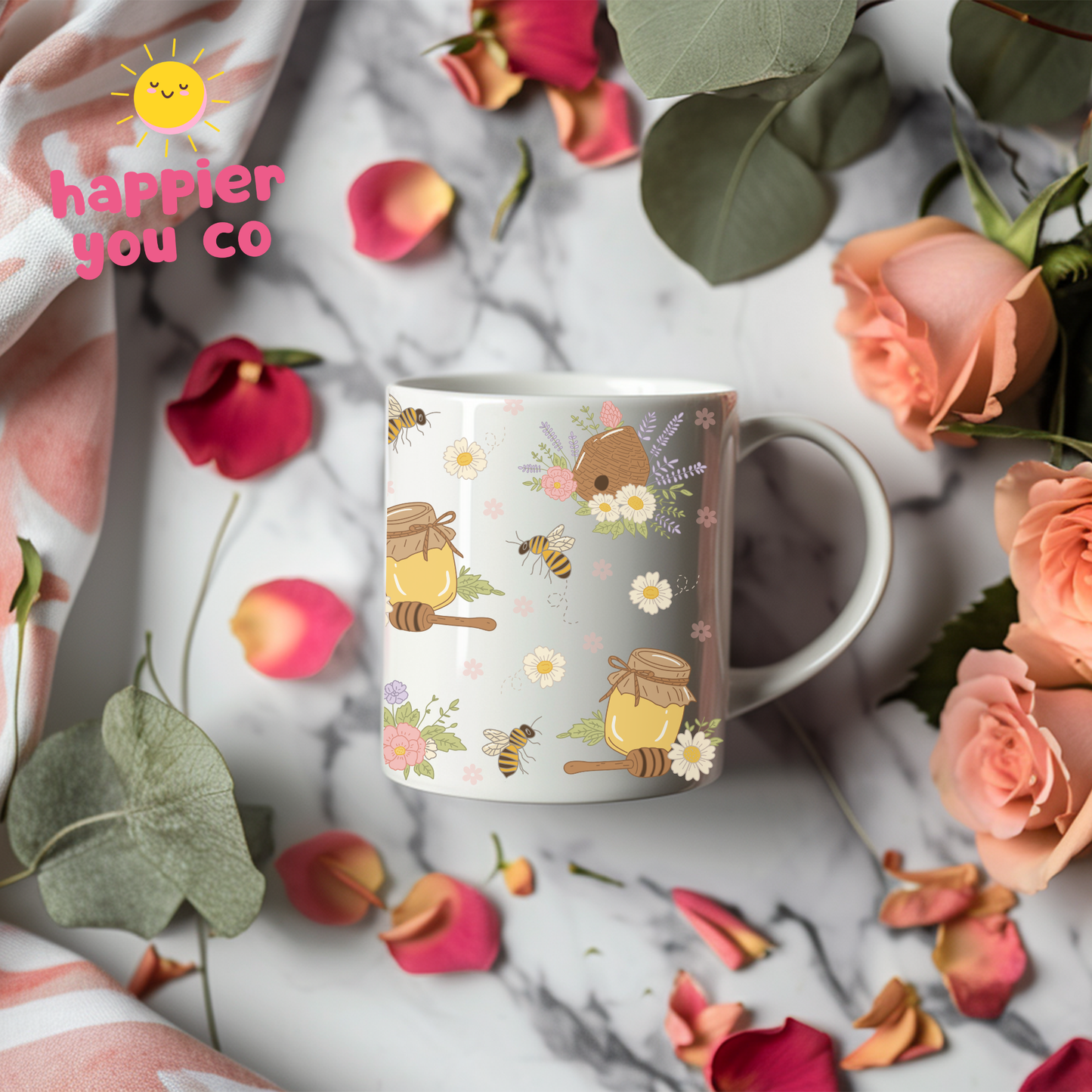 Mug with floral and bee design on a marble surface with flowers and leaves.