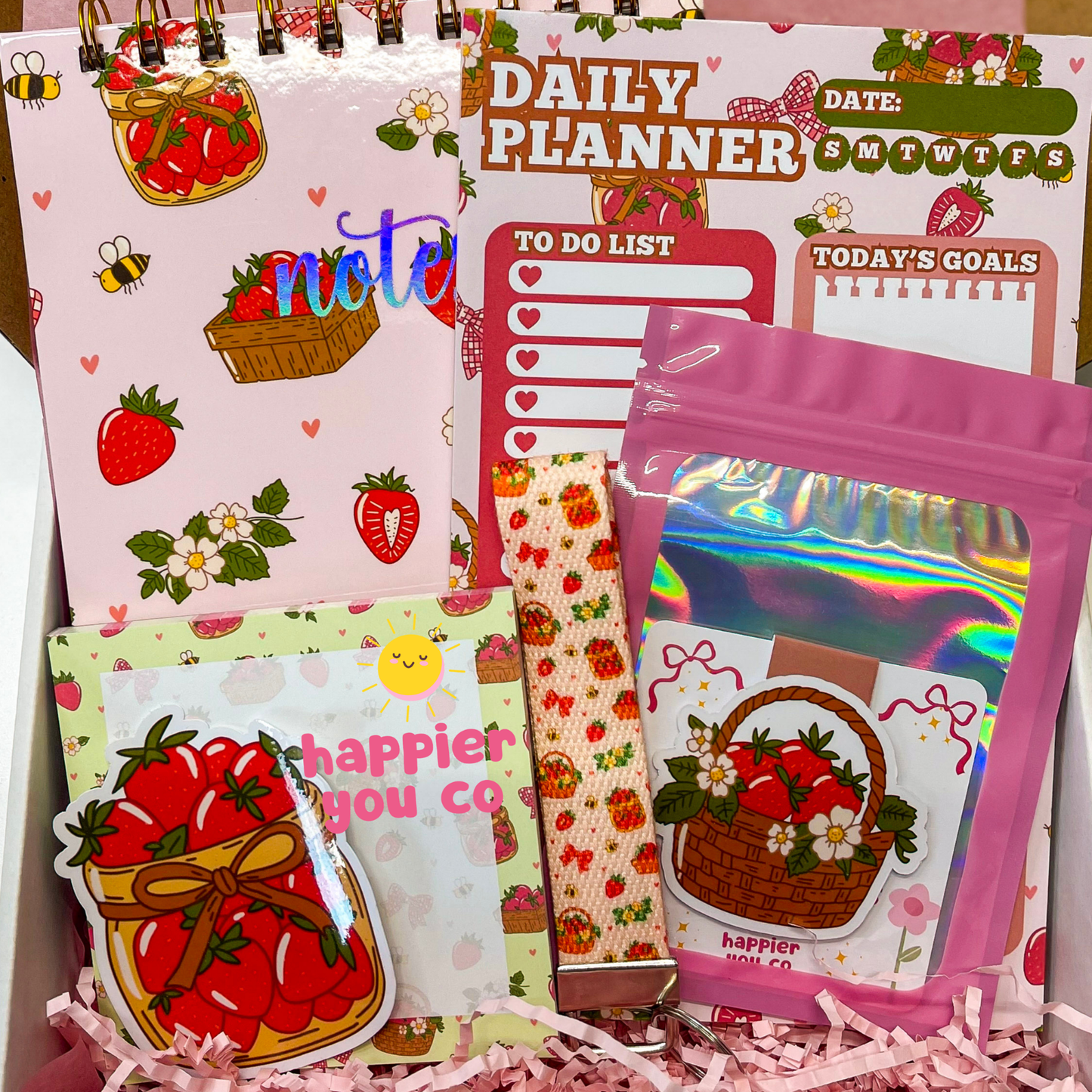 Collection of stationery items with strawberry designs and text on a pink background