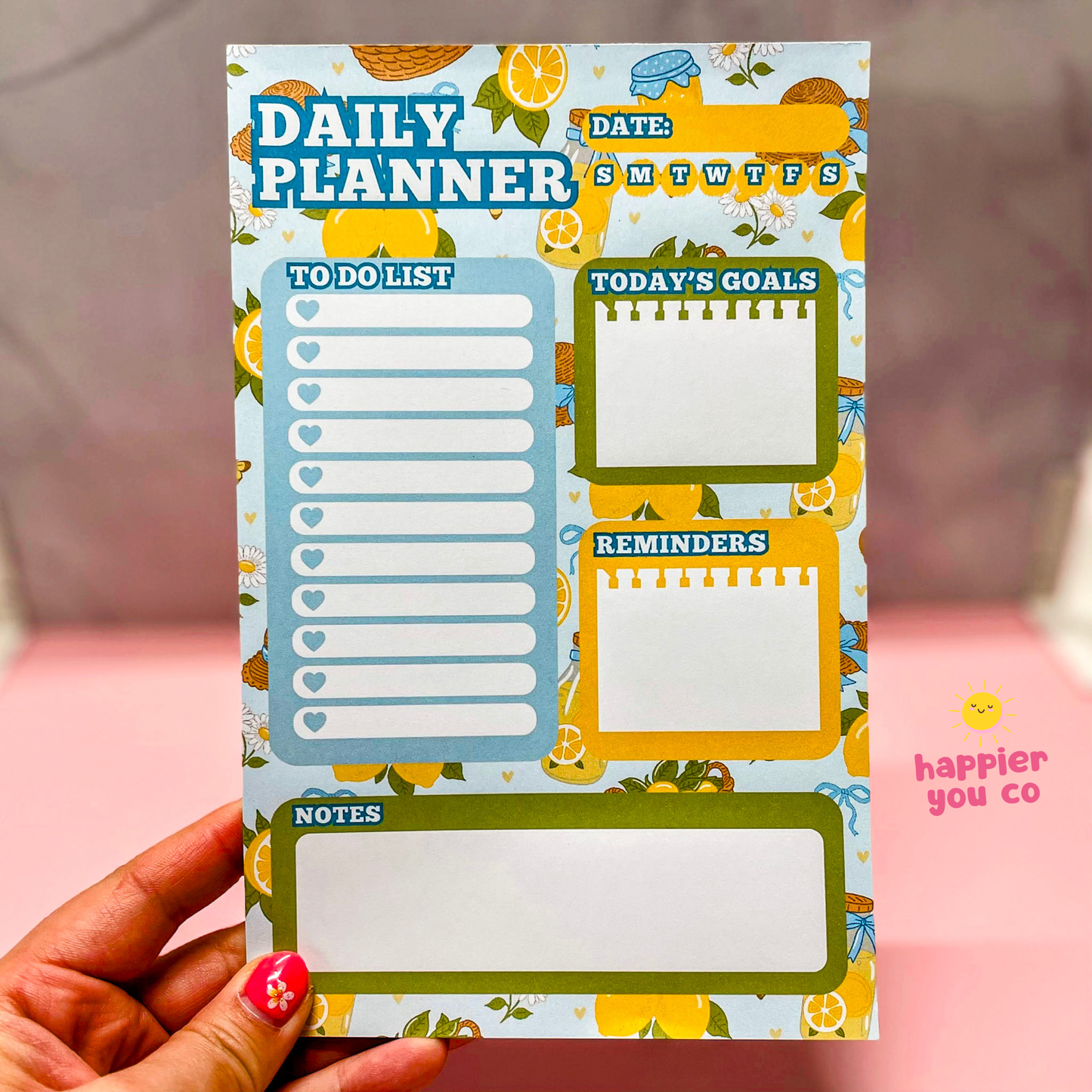 Daily planner with colorful design held by a hand, featuring sections like 'To Do List', 'Today's Goals', and 'Reminders'.