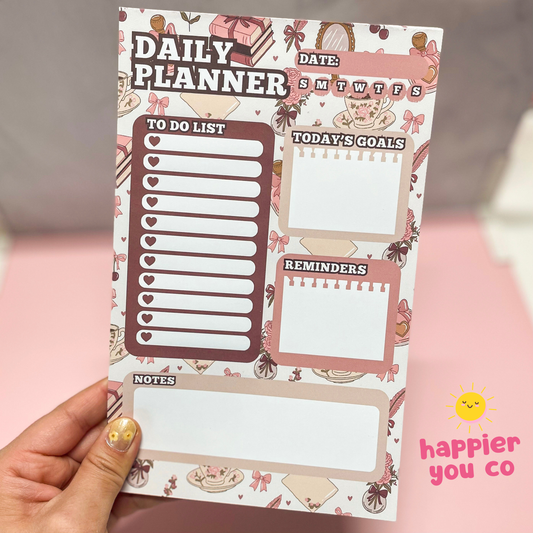 Daily planner sheet with various sections on a pink background, held by a hand.
