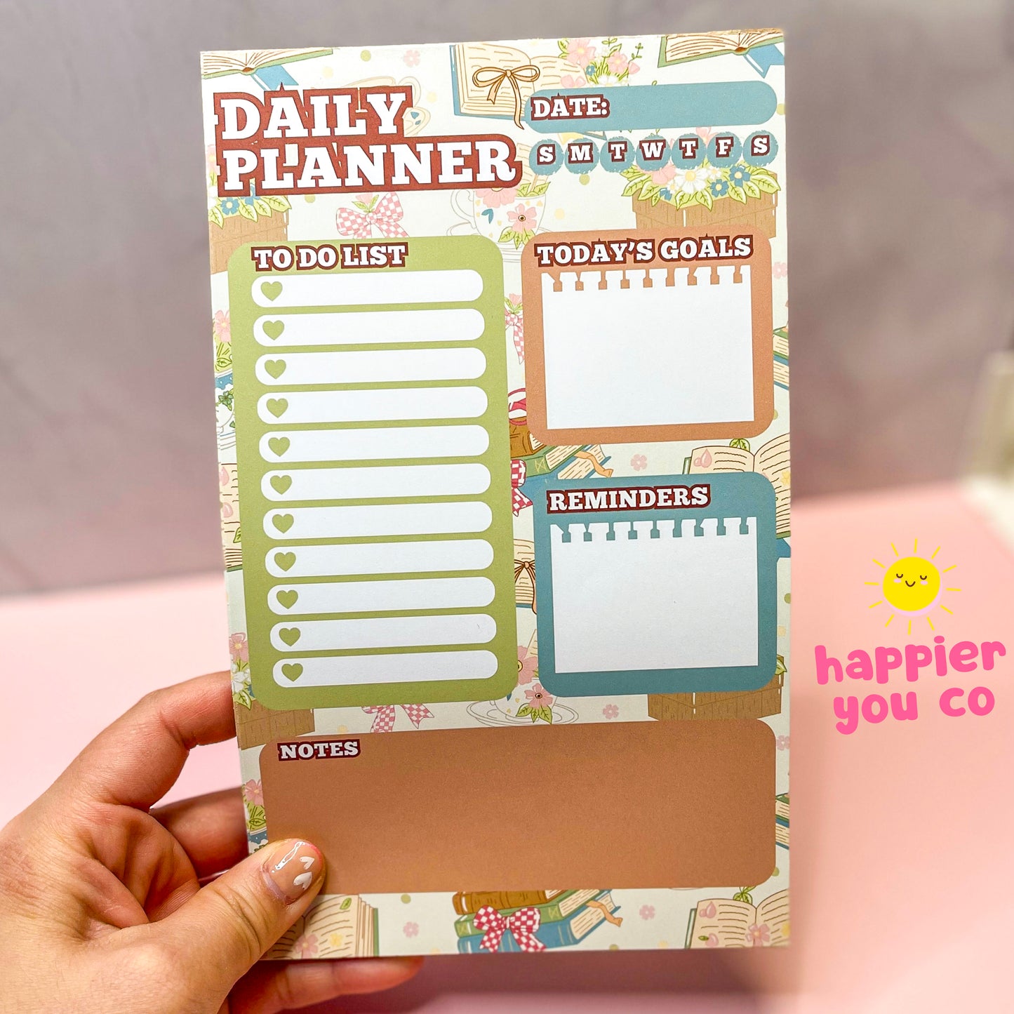 Hand holding a colorful daily planner with various sections on a neutral background.