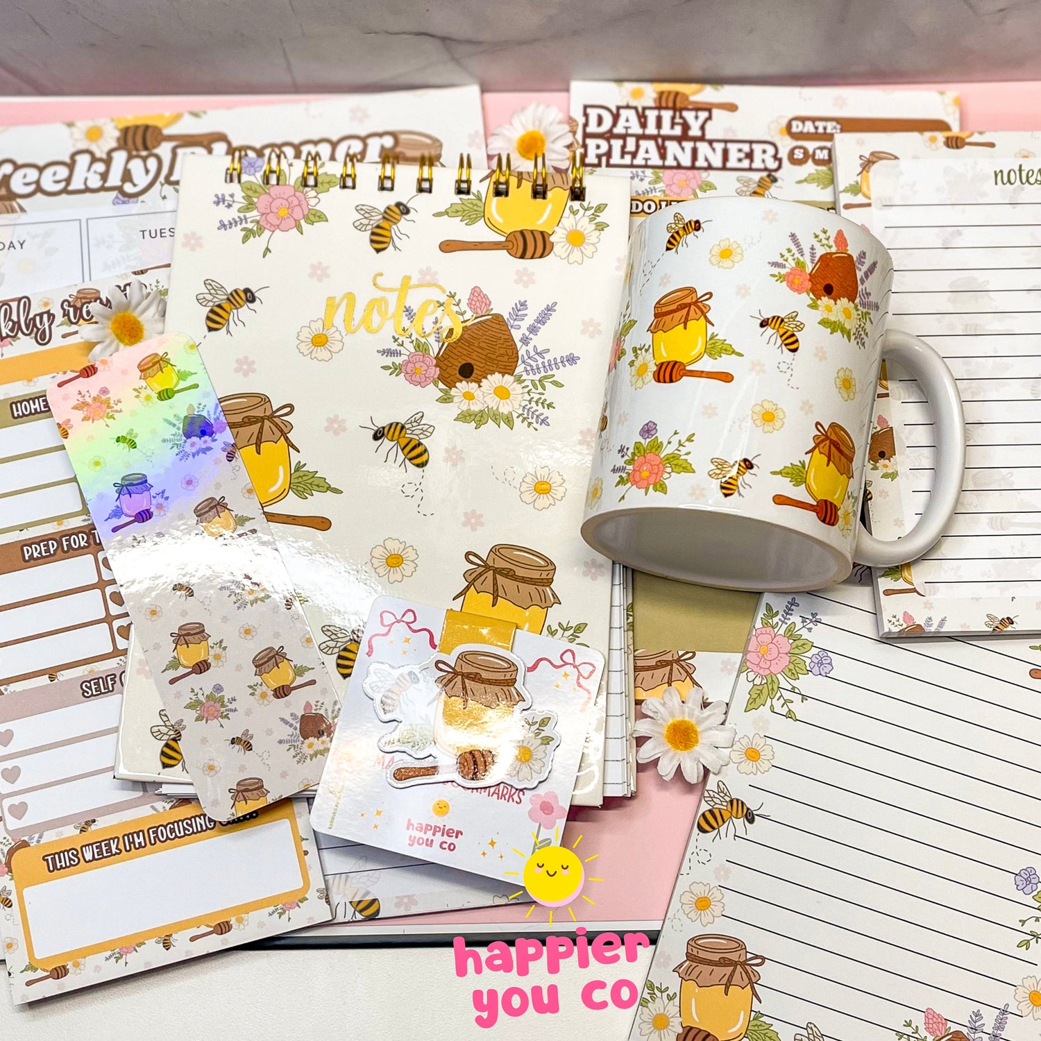 Variety of stationary products that includes notepads, notebooks, planners, bookmarks featuring a floral honey bee design