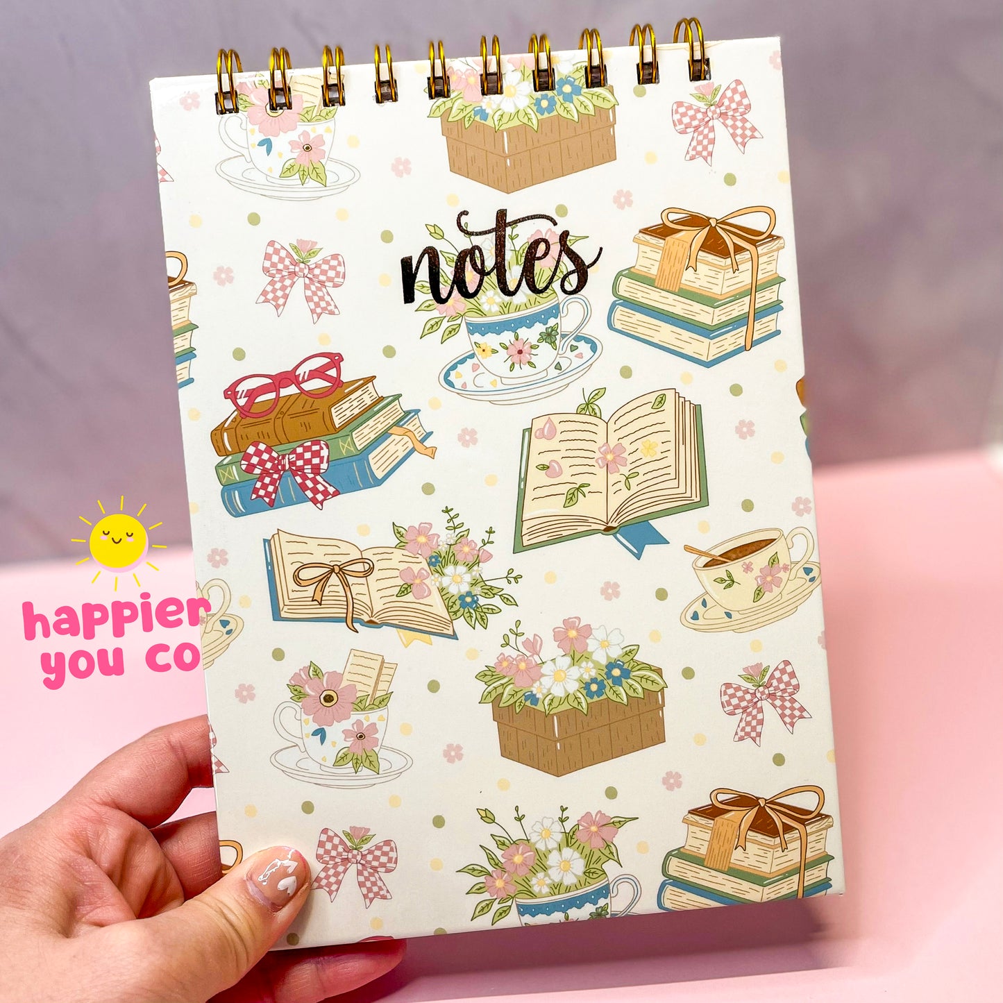 Notebook with decorative cover held by a hand on a pink background