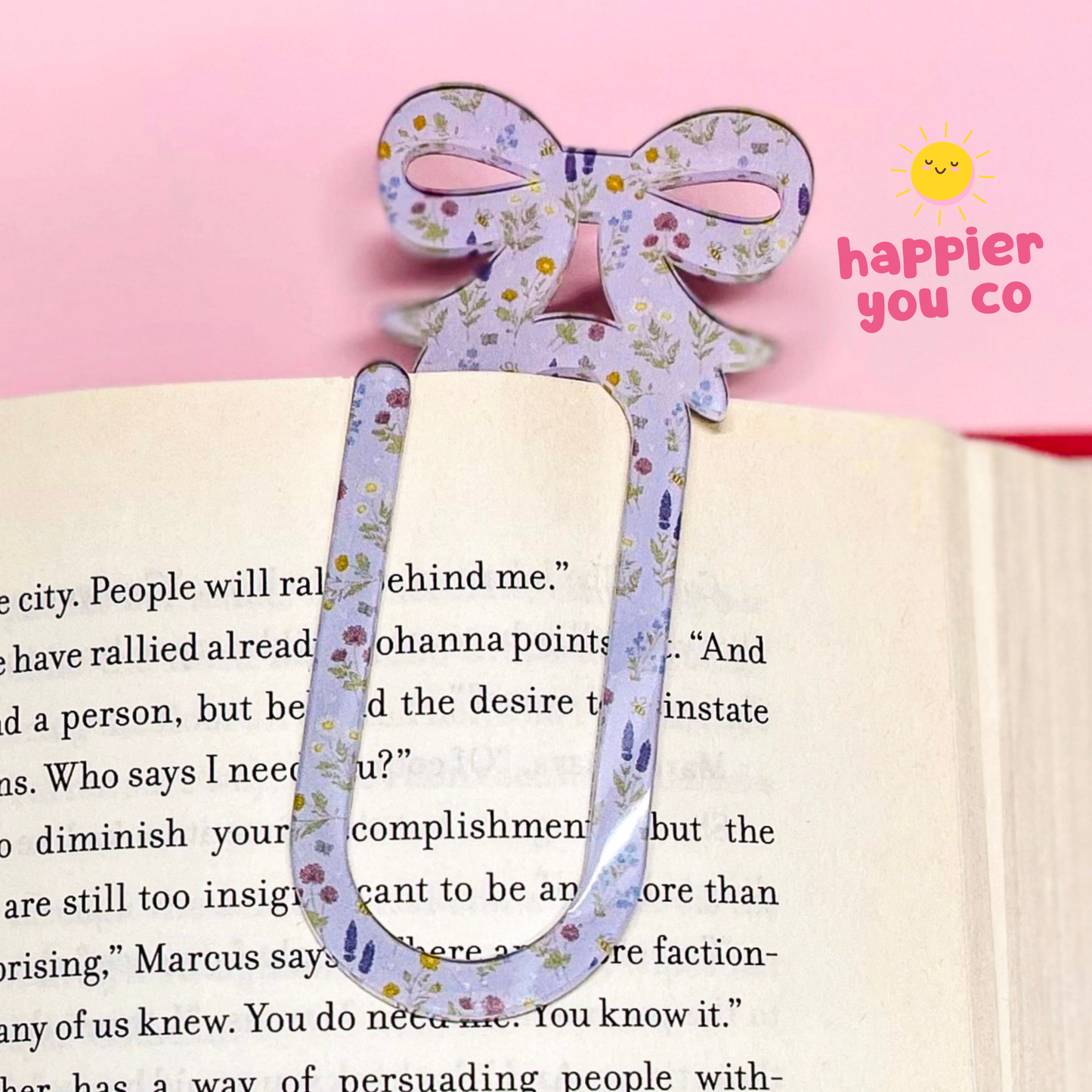 Decorative floral bookmark on an open book with 'happier you co' branding.