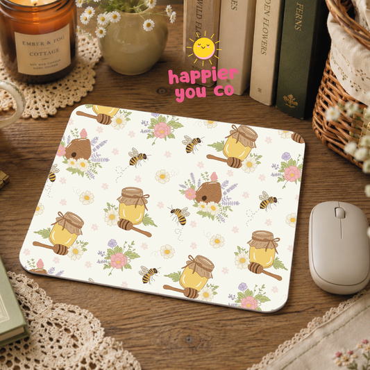 Mouse pad with honeycomb and bee design on a wooden desk with books and a candle.