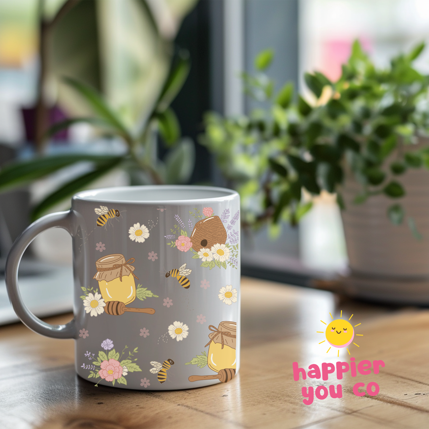 White mug with bee and honey design on a wooden table with 'happier you' branding.