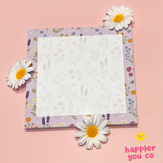 Notepad with floral design on a pink background with daisy flowers.
