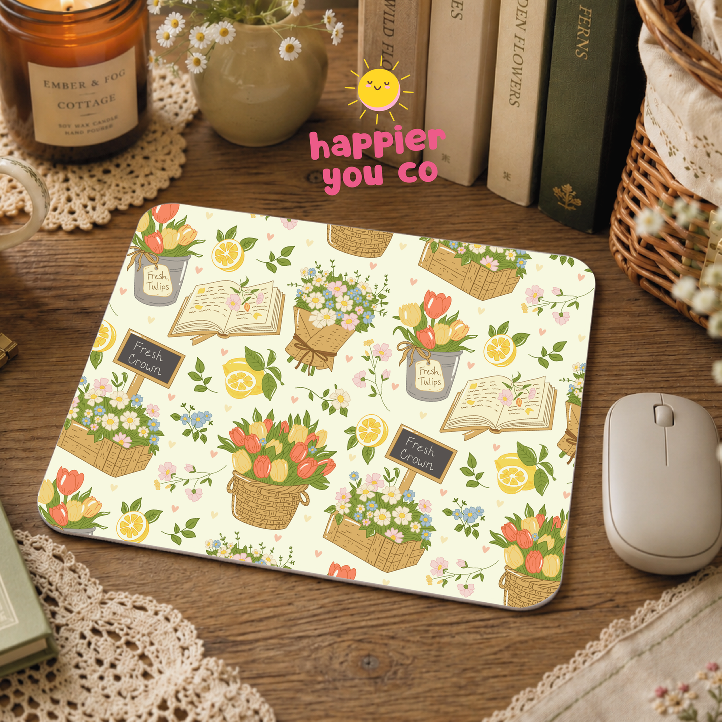 Mouse pad with floral and book design on a wooden desk, featuring 'happier you co' text.