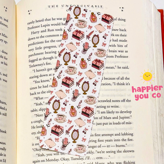 Decorative bookmark with illustrations of tea cups, cakes, and other items on a page with text.