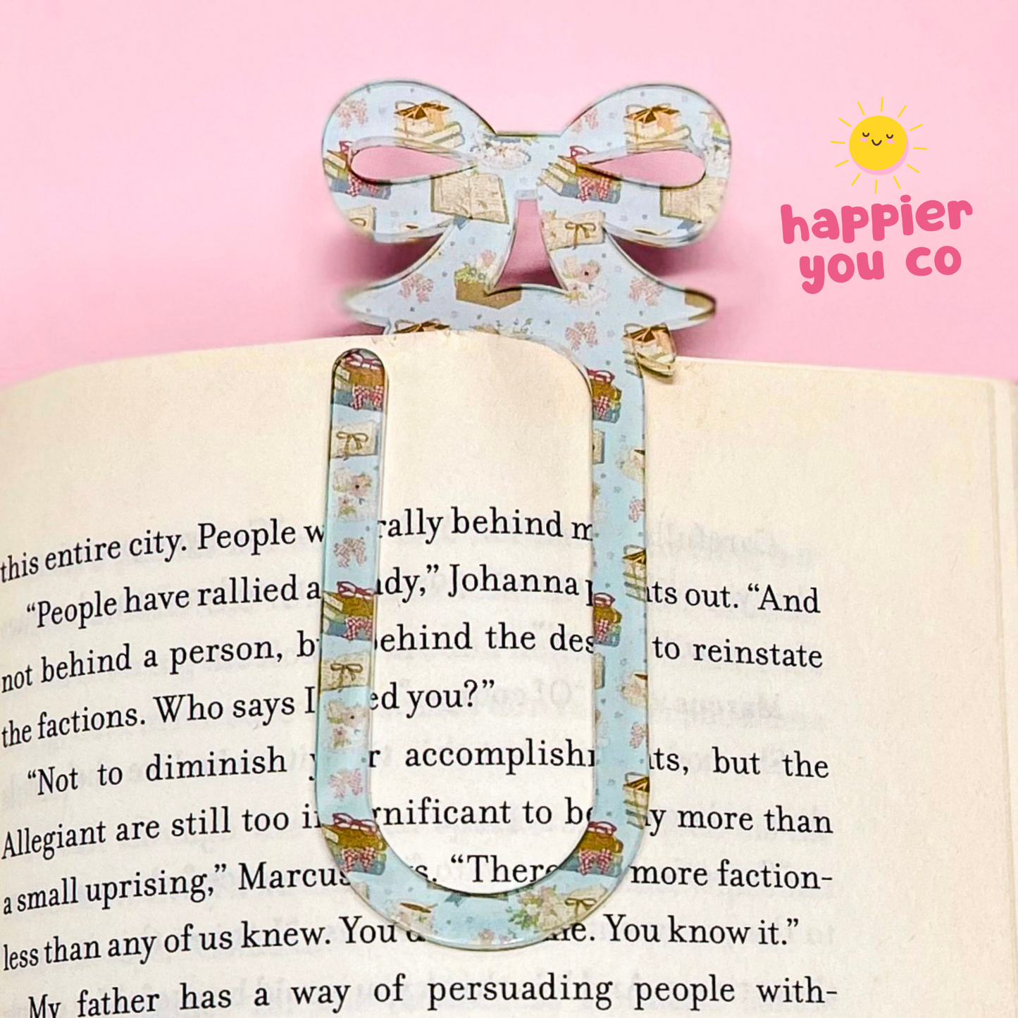 Decorative bookmark with floral design on an open book, featuring 'happier you co' branding.