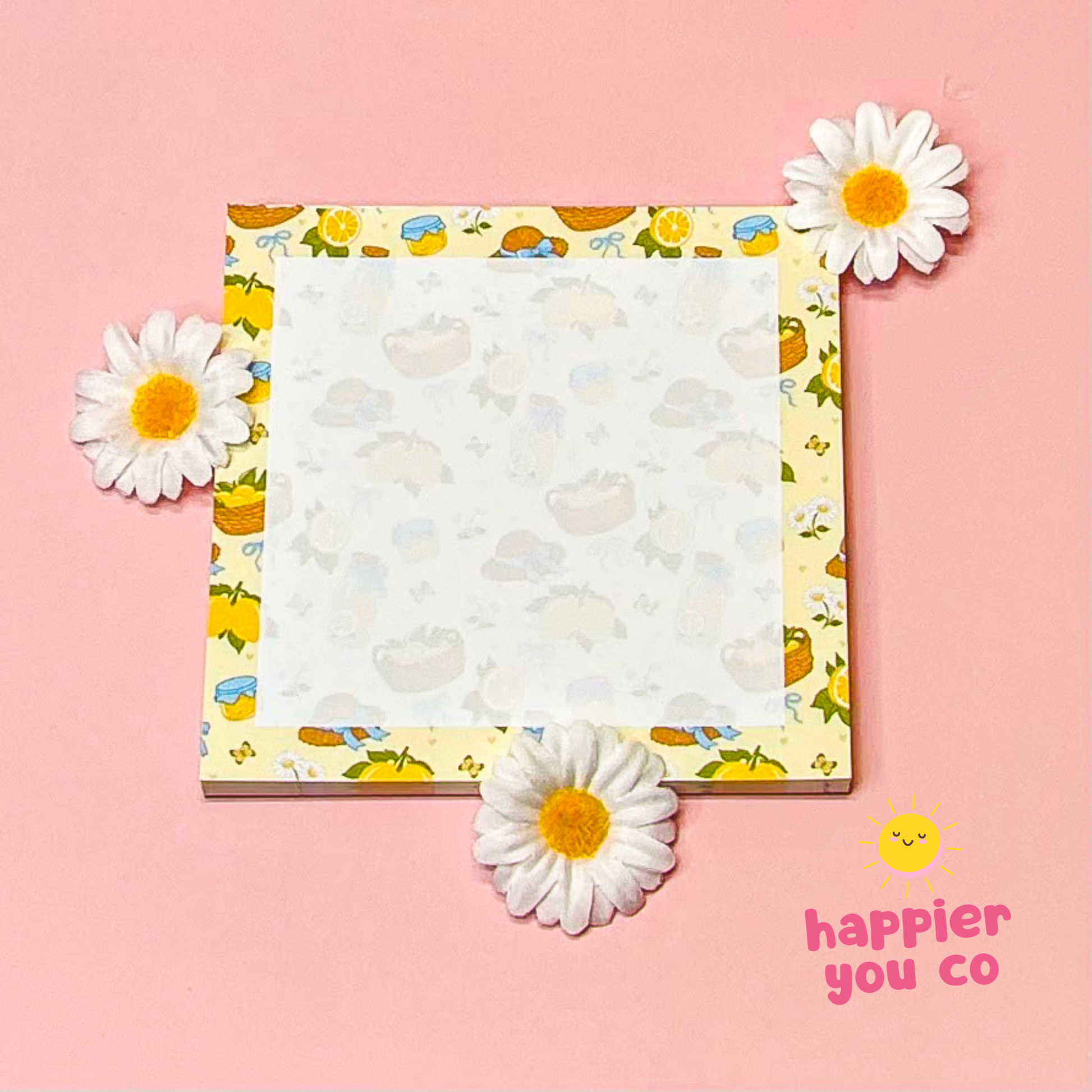 Notebook with floral design on a pink background with daisies and 'happier you co' branding.