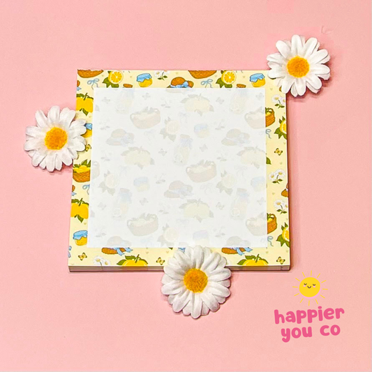 Notebook with floral design on a pink background with daisies and 'happier you co' branding.
