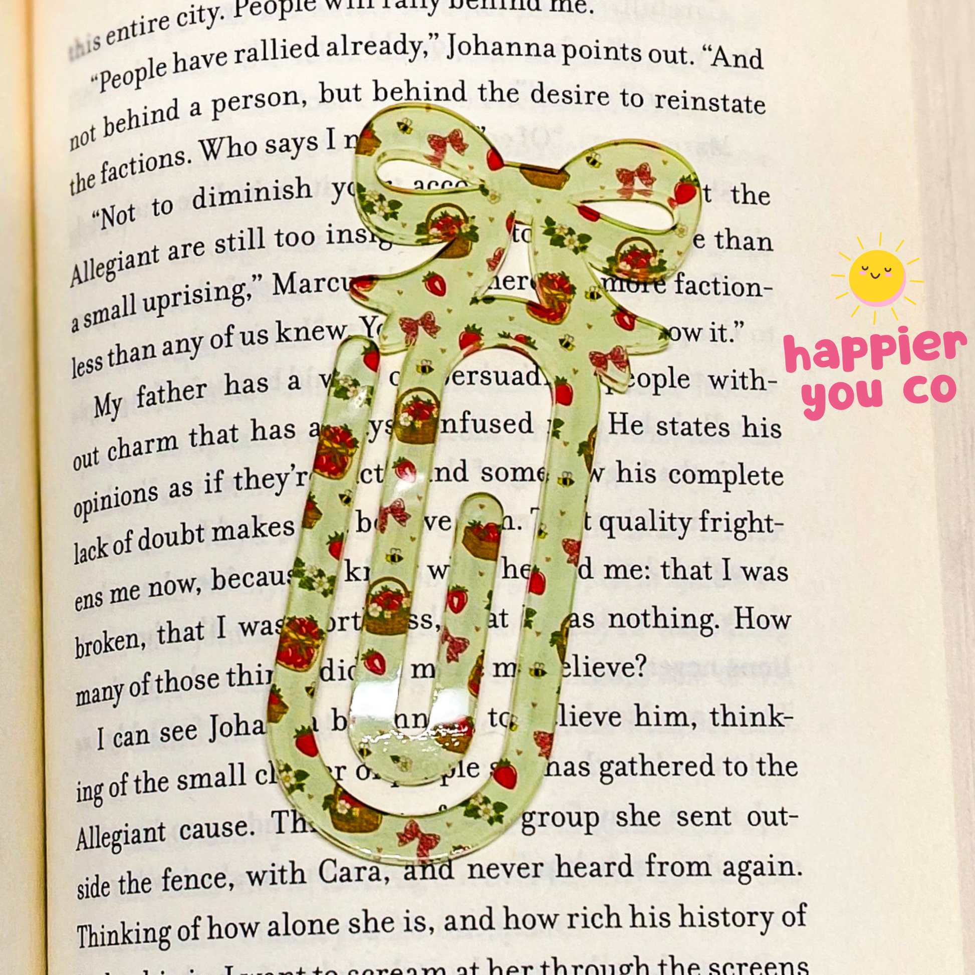 Decorative paper clip with floral pattern on an open book, featuring 'happier you co' branding.