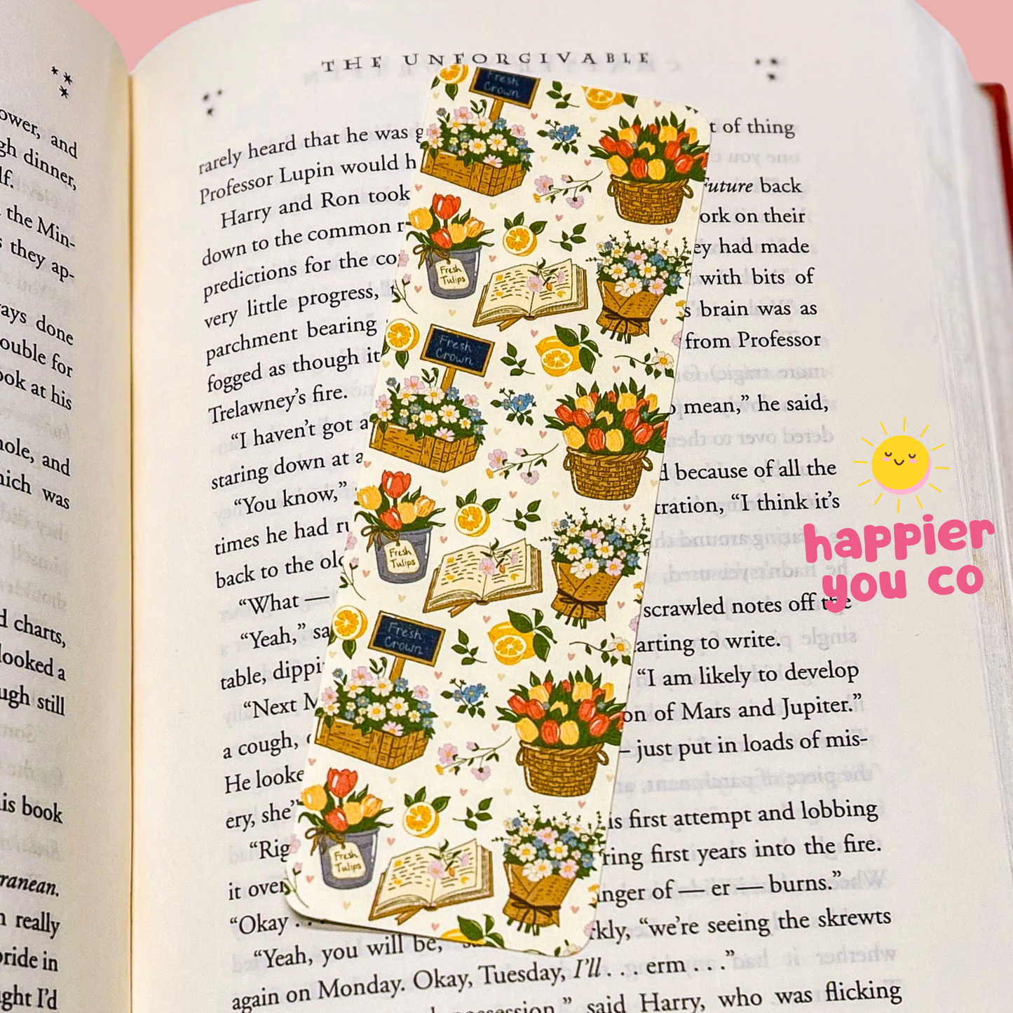Open book with decorative flowers and books on a pink background