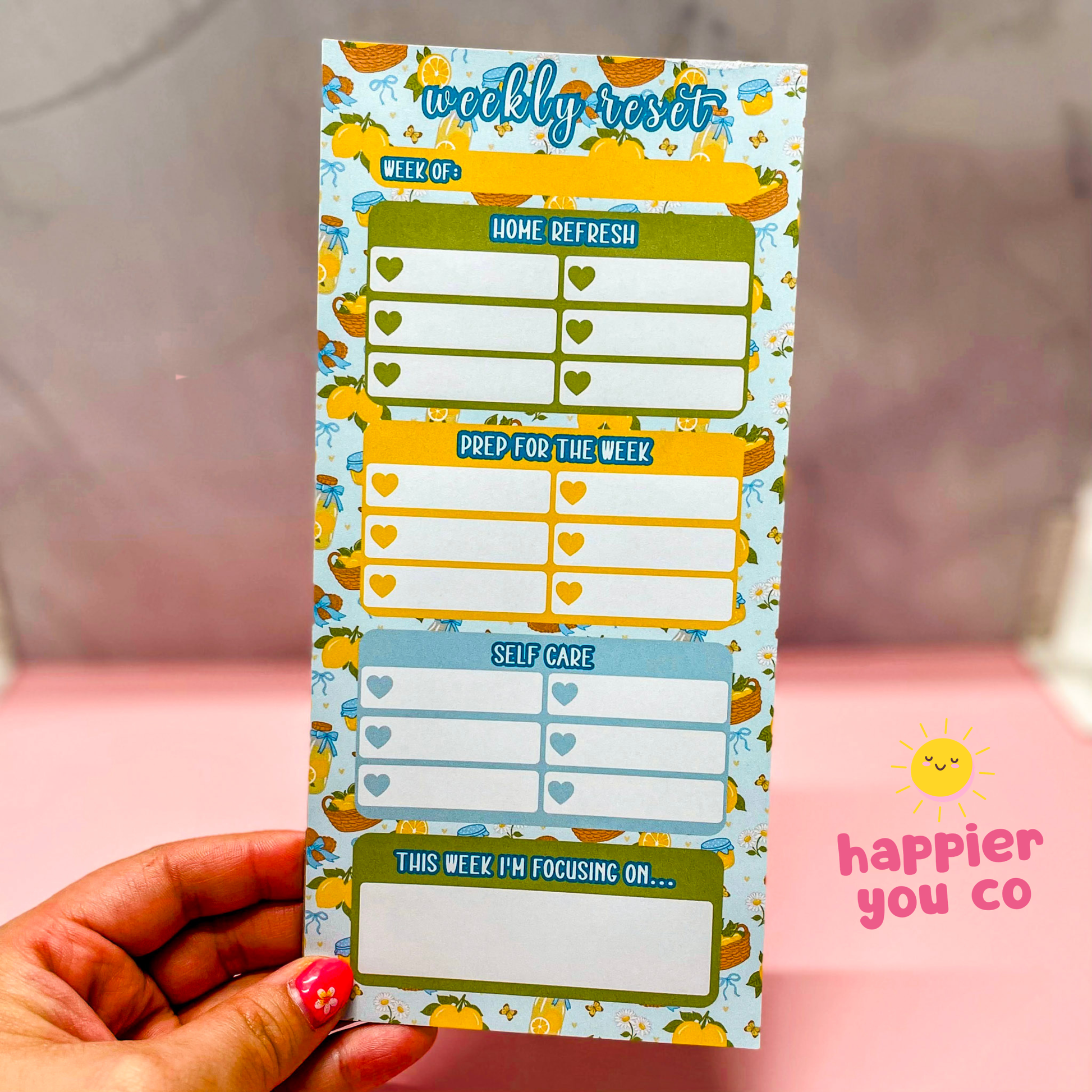 Weekly planner with colorful design held by a hand, featuring 'happier you co' branding.