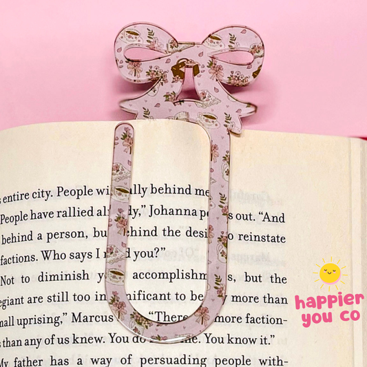Decorative  bookmark with floral design on an open book against a pink background.