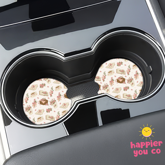 Two floral-patterned coasters in a car cup holder with 'happier you co' branding.