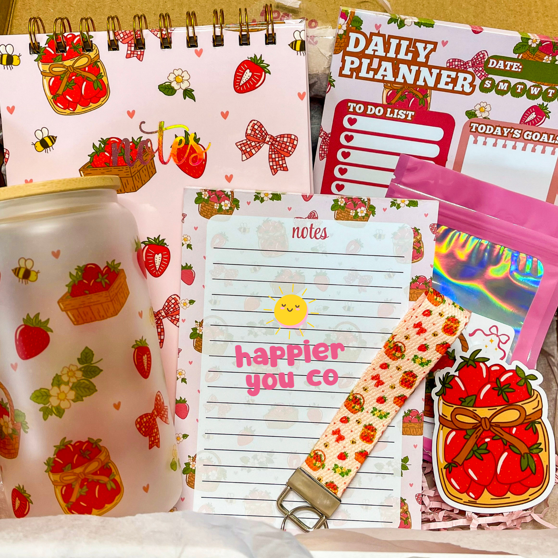 Collection of stationery items including a planner, notepad, and strap with strawberry design.