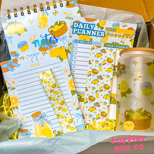Set of stationery items with lemon-themed design including a planner, notepad, and cup.