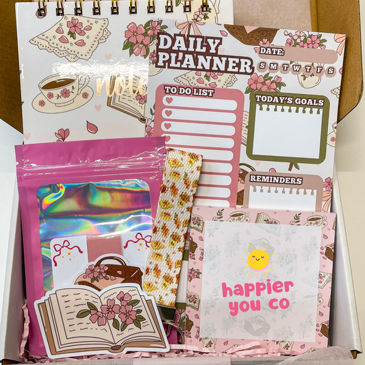 Collection of stationery items including a planner, stickers, and a pink pouch on a wooden surface.