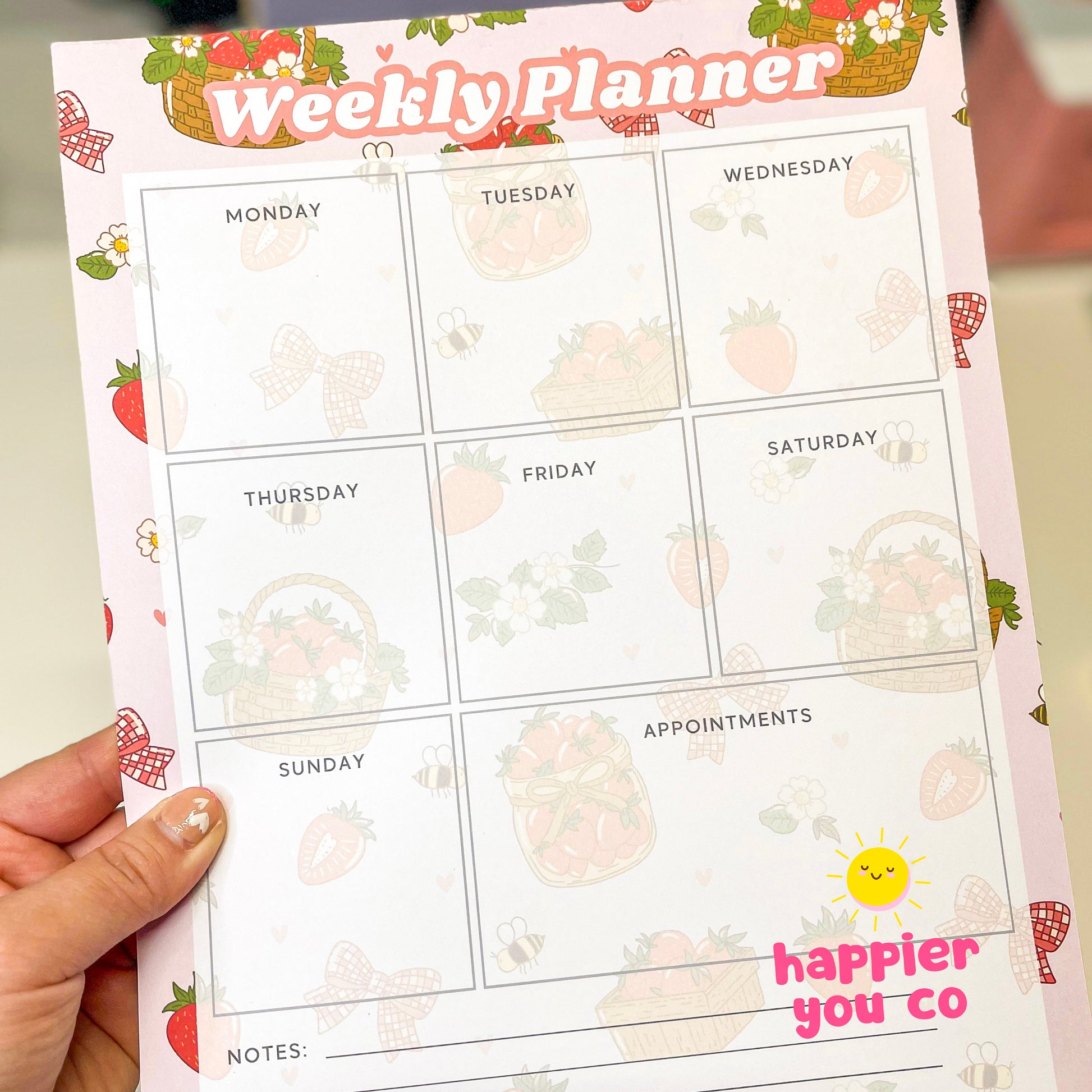 Weekly planner notepad with  floral strawberry background help by a hand