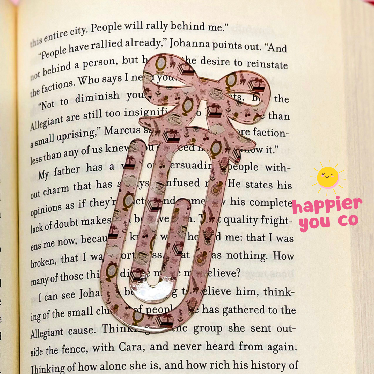 Decorative pink paperclip on a book with 'happier you co' branding.