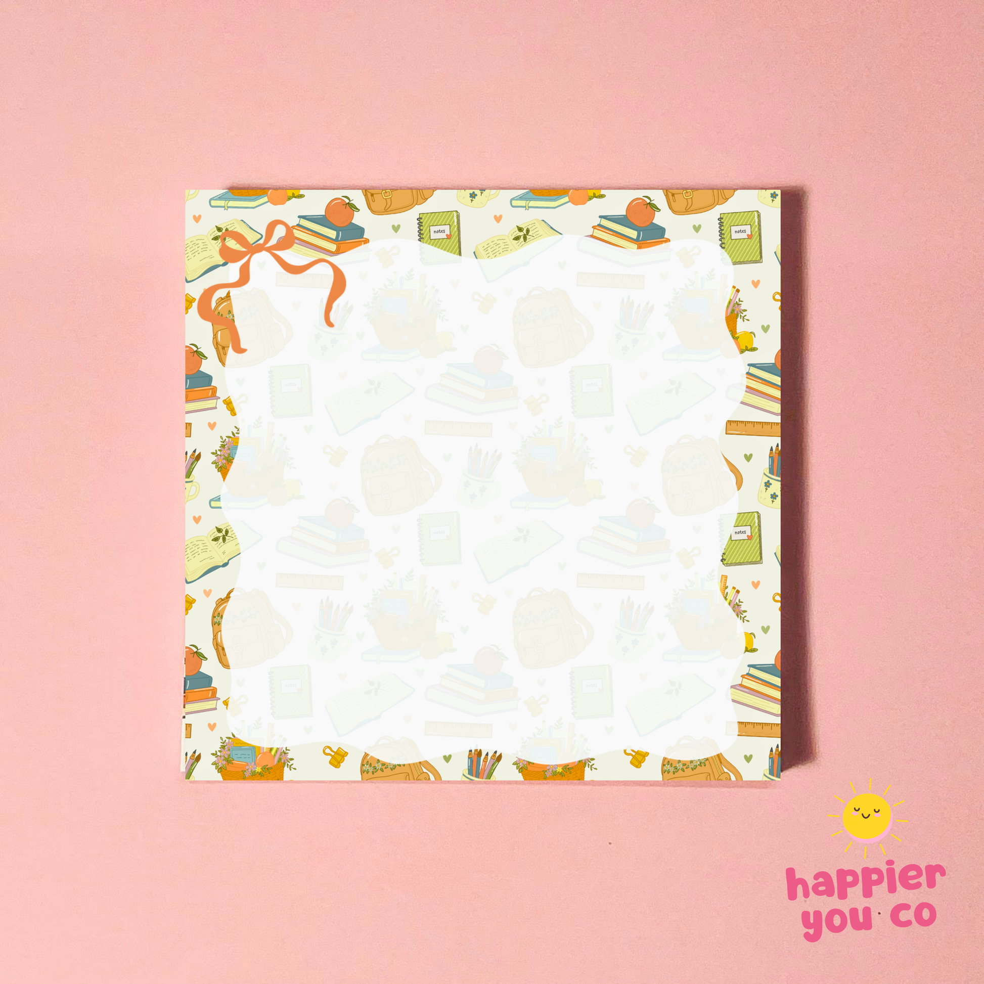 A square white notepad with a colorful illustrated border featuring books, pencils, sticky notes, and a ribbon, placed on a solid pink background. The 'happier you co' logo is visible in the bottom right corner.