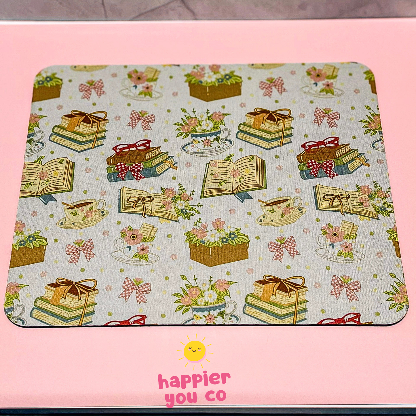 Mouse pad with decorative pattern on a pink background, featuring the brand 'happier you co'.