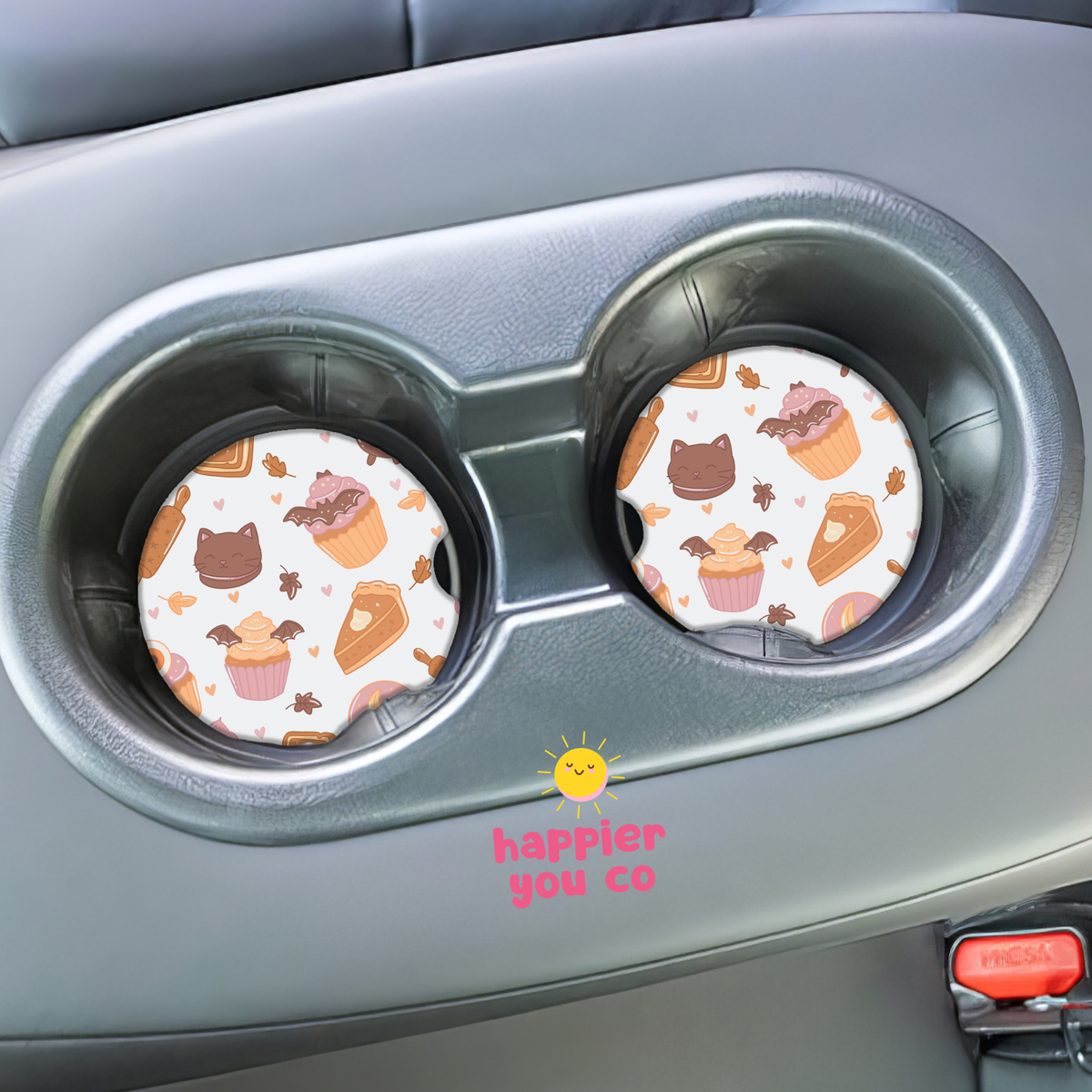 Two round car cup holder covers with a cute dessert pattern of cupcakes, cakes, and cookies, shown installed in a gray dual cup holder inside a car.
