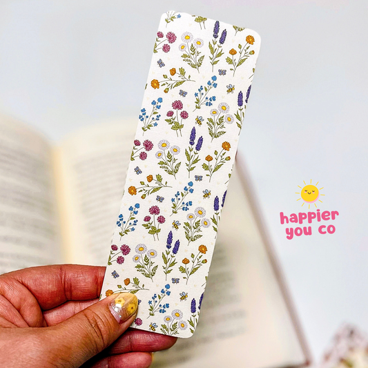 Floral-patterned bookmark held by a hand with 'happier you co' branding.