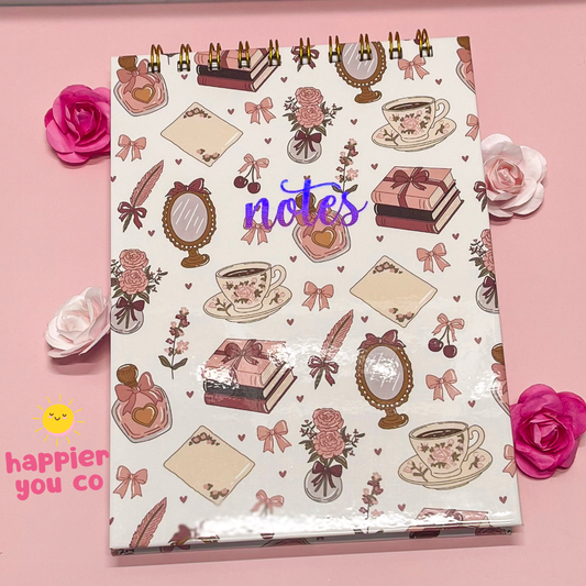 Notebook with decorative cover on a pink background with flowers