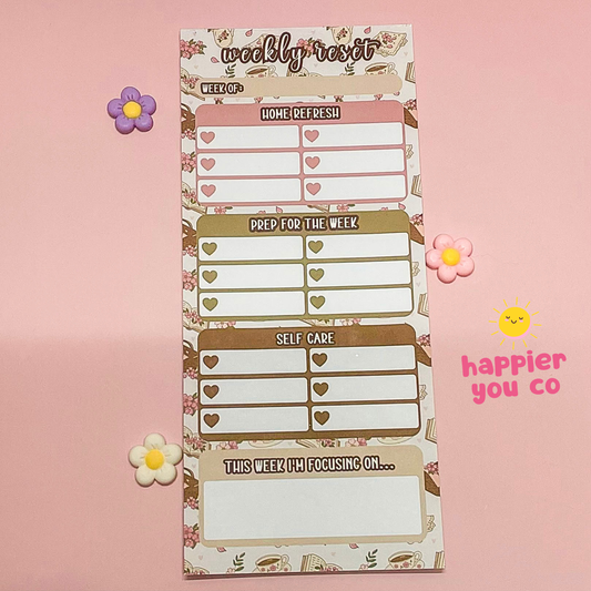 Weekly planner notepad with decorative elements on a pink background