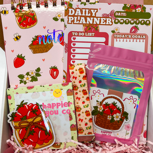 Collection of stationery items with strawberry designs and text on a pink background