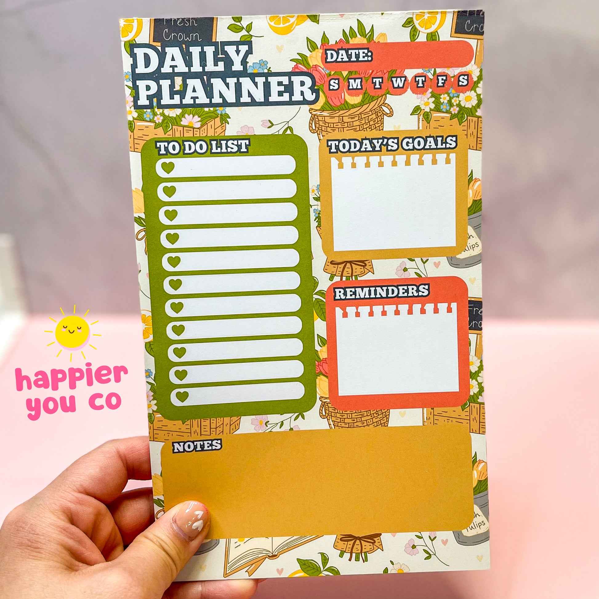 Hand holding a colorful daily planner with various sections.