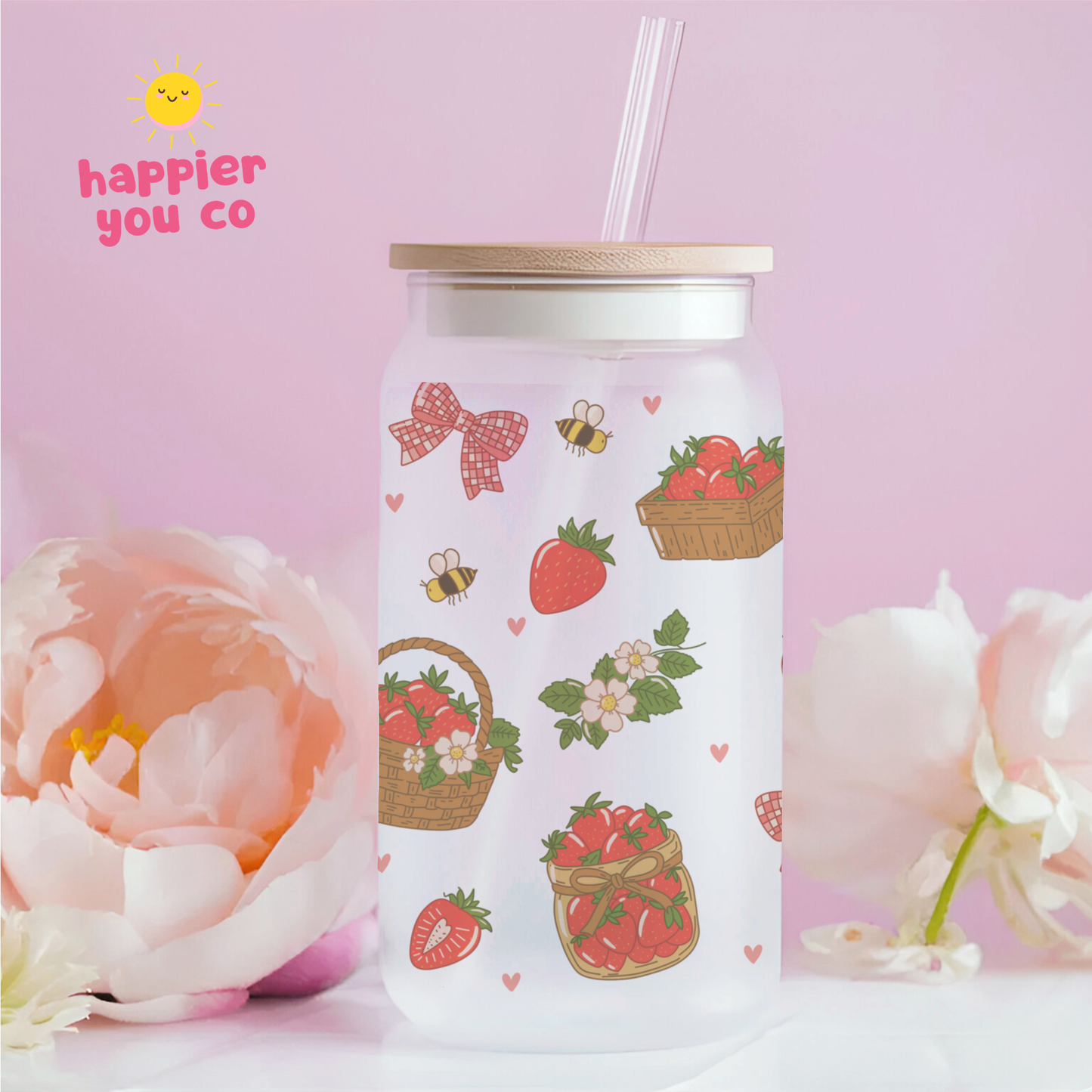 White tumbler with strawberry and basket design on a pink background with flowers.