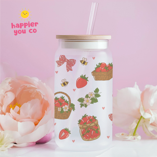 White tumbler with strawberry and basket design on a pink background with flowers.