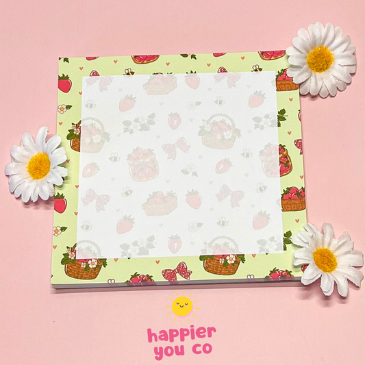 Notepad with a colorful floral design on a pink background, featuring the brand 'happier you co'.