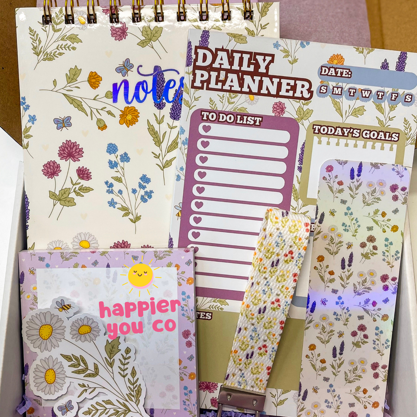 Notebook with floral design, 'Daily Planner' with to-do list and goals, and a small pouch with floral pattern.