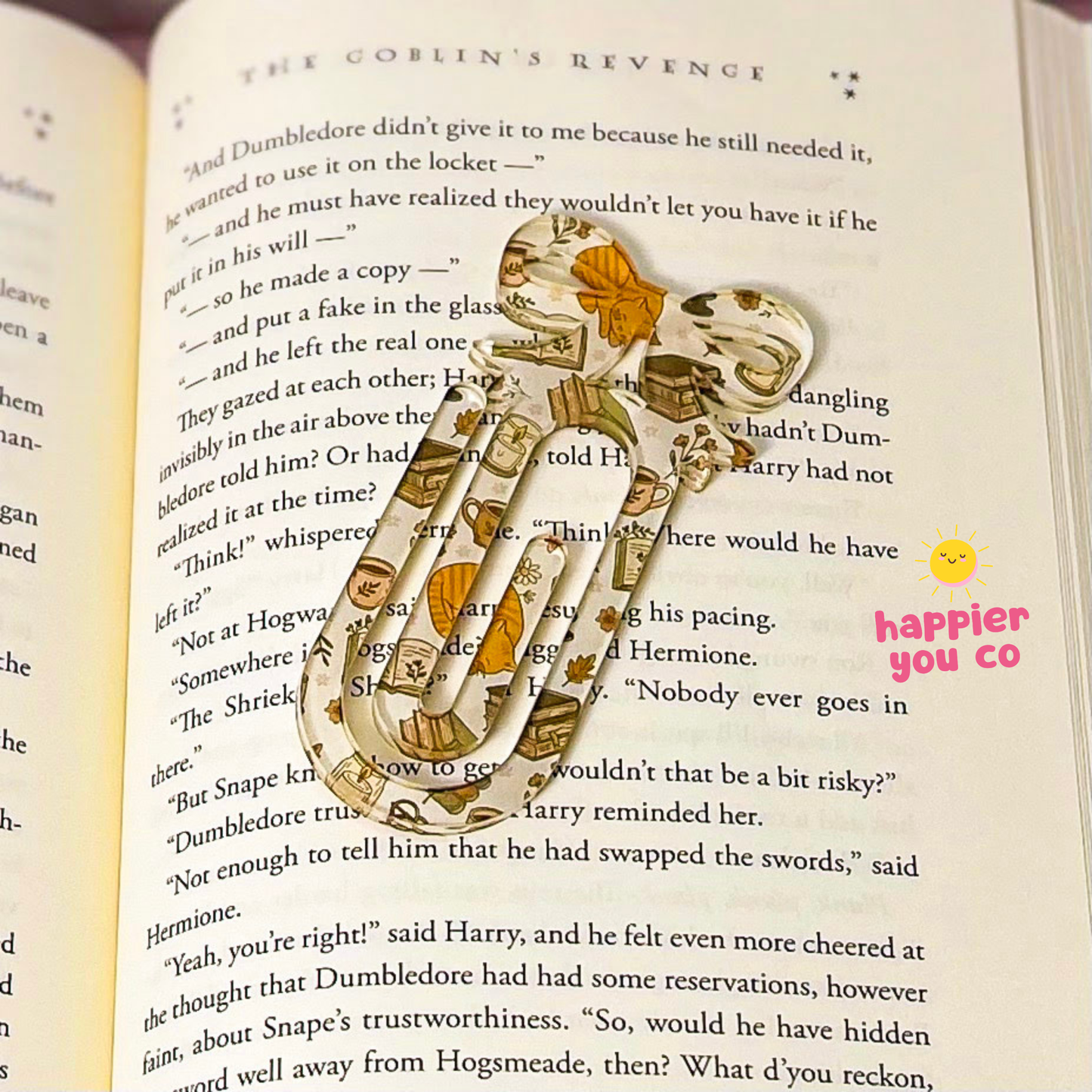A decorative book bookmark shaped like a pair of gold and brown leather shoes with orange accents, placed on the pages of an open book titled 'The Goblin's Revenge'.