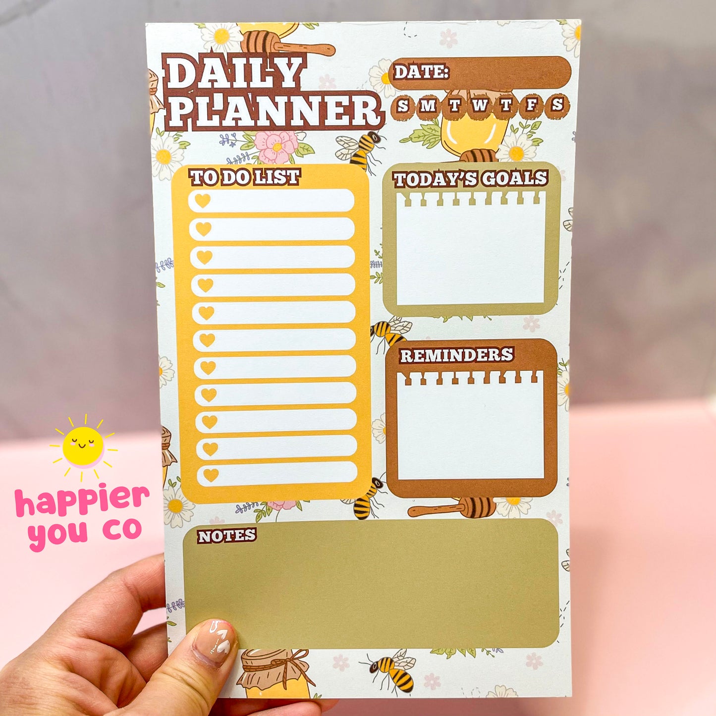 Daily planner with to-do list, goals, reminders, and notes sections held by a hand.