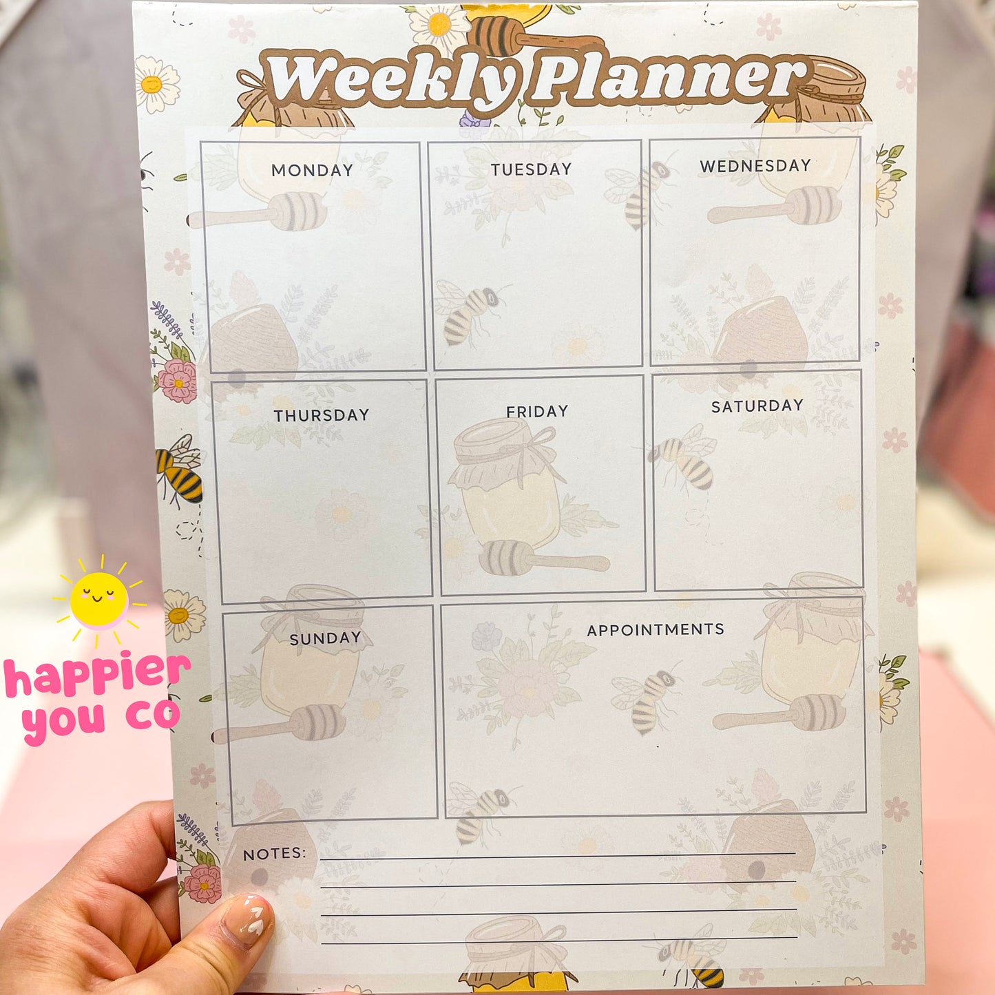 Weekly planner sheet with cartoon bee design held by a hand