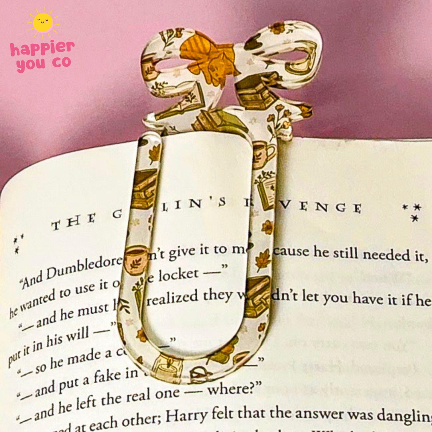 A decorative paper bookmark shaped like a bow with a ribbon bookmark core, printed with a vintage Harry Potter character pattern, resting on an open book page against a pink background.