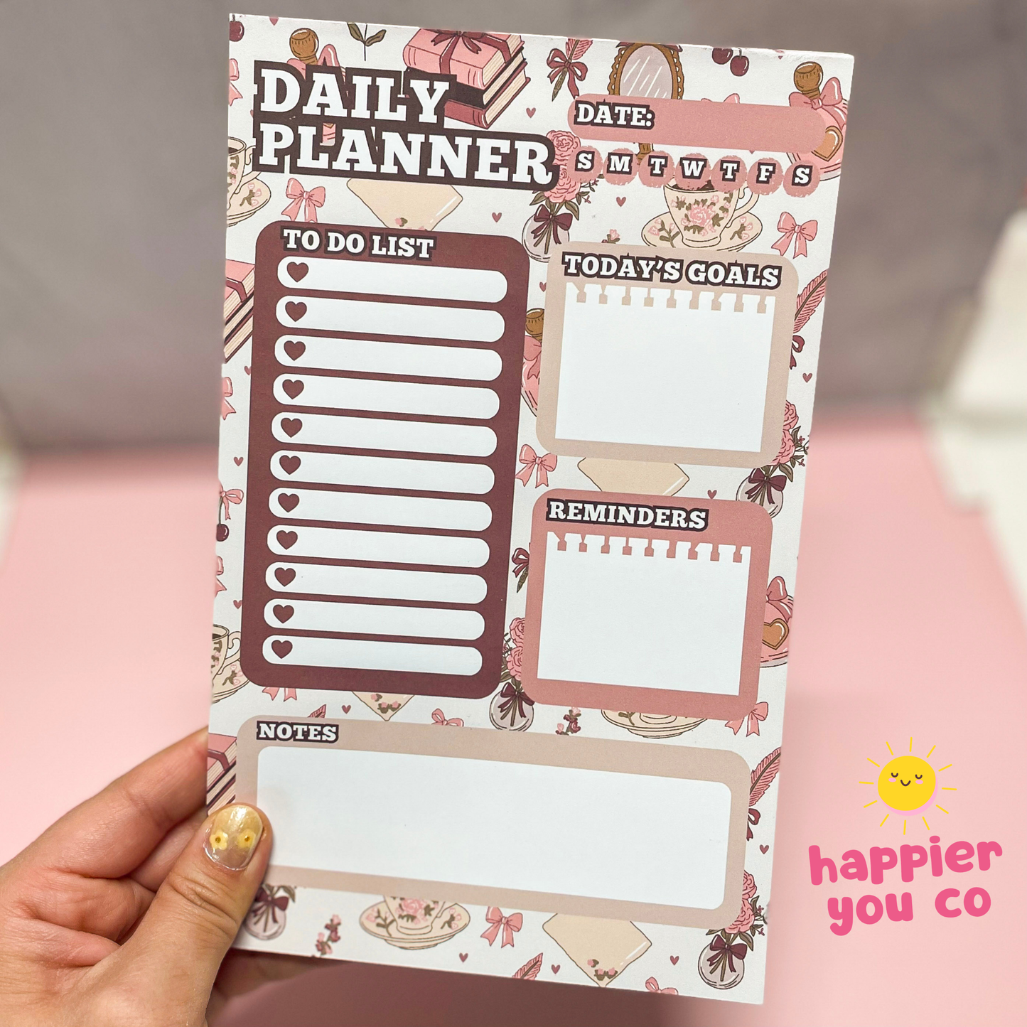 Daily planner sheet with various sections on a pink background, held by a hand.