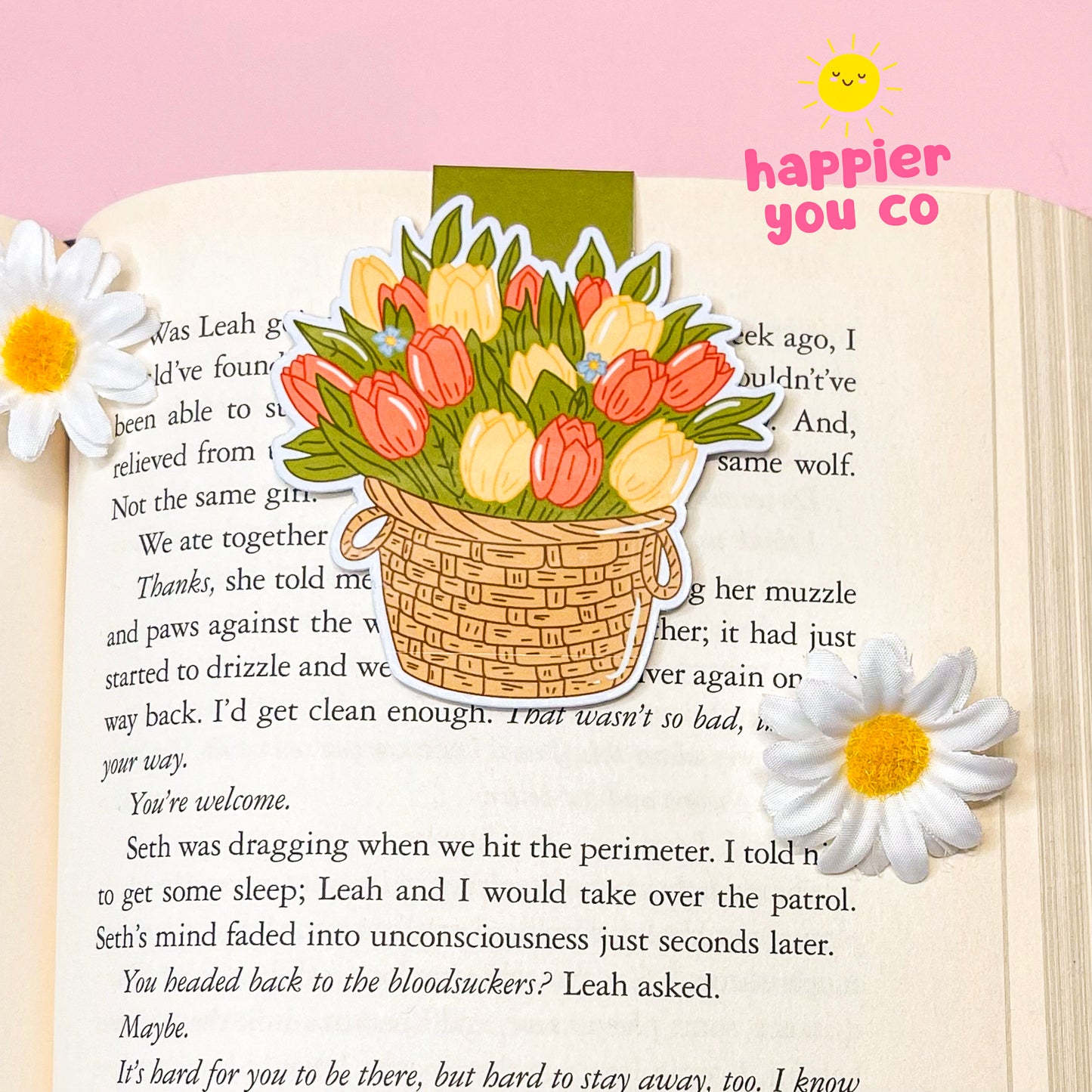 Floral bookmark with a basket of tulips on an open book, featuring the brand 'happier you co'.