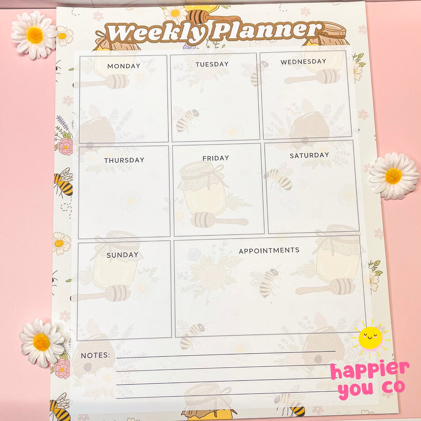 Weekly planner sheet with bee and honeycomb design on a pink background, featuring the 'happier you co' brand.