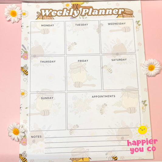 Weekly planner sheet with bee and honeycomb design on a pink background, featuring the 'happier you co' brand.