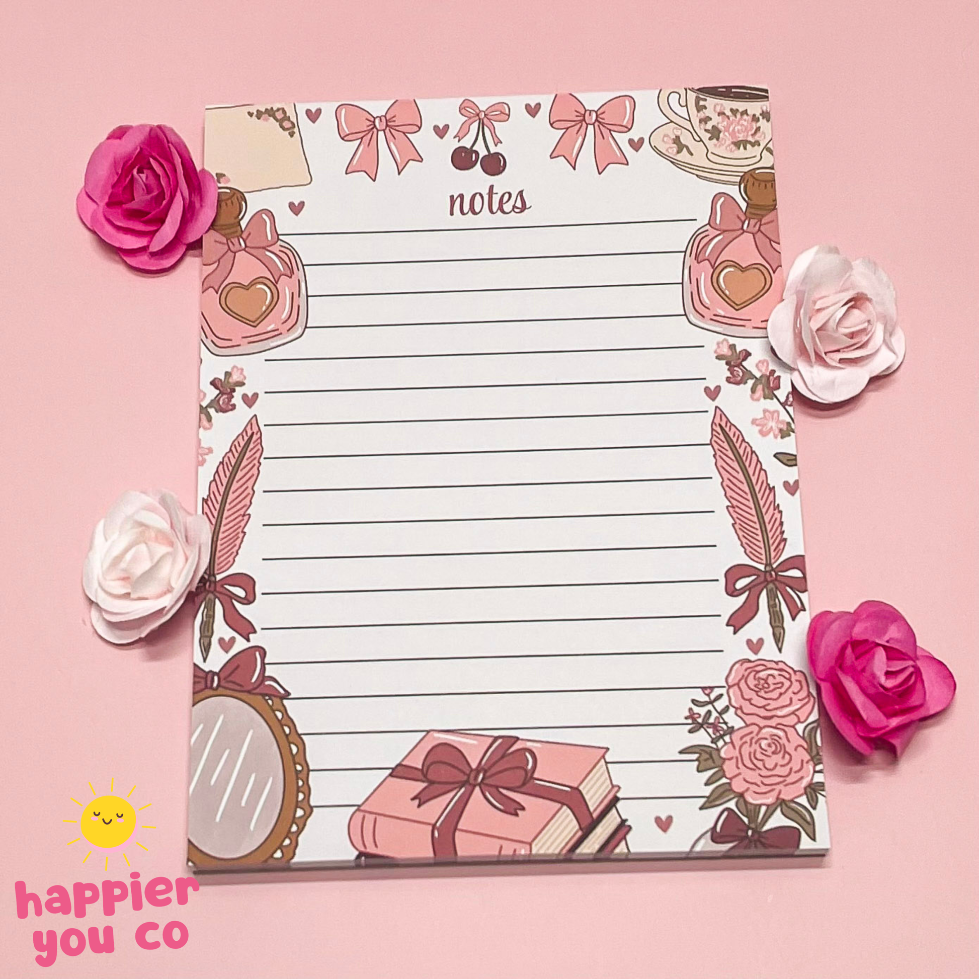 Decorative notepad with floral and gift designs on a pink background, featuring the brand 'happier you co'.