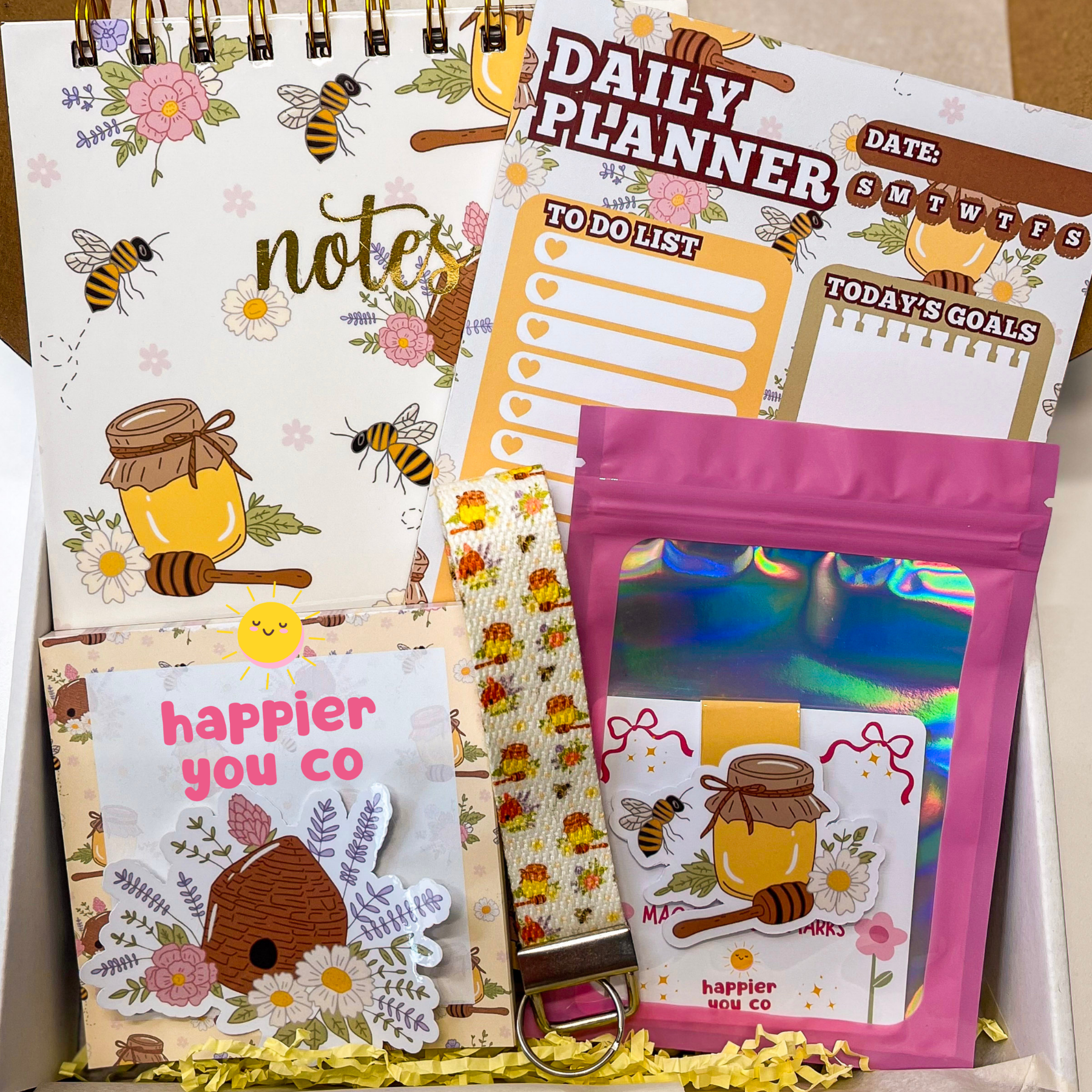 Collection of stationery items including a planner, cards, and a bag with bee-themed designs.