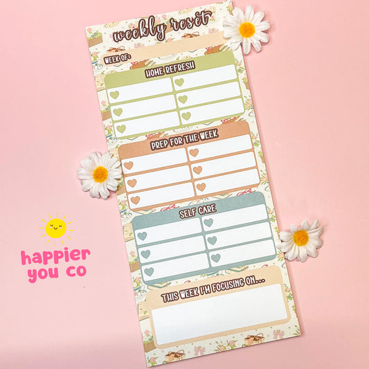 Weekly planner with floral design on a pink background, featuring the brand 'happier you co'.