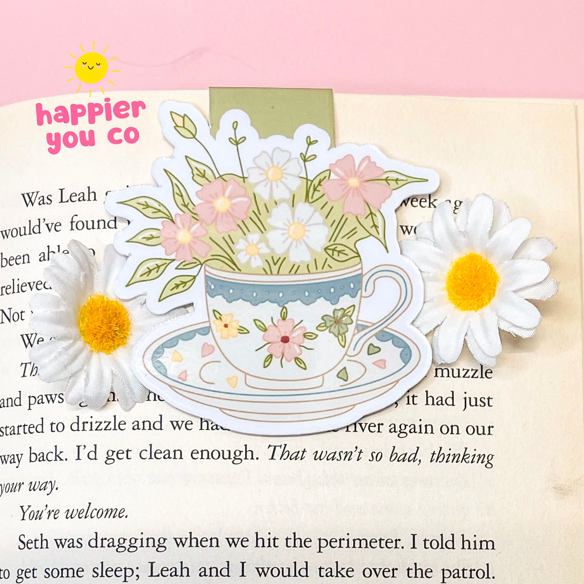 Decorative magnetic bookmark of a teacup with flowers on a book page.